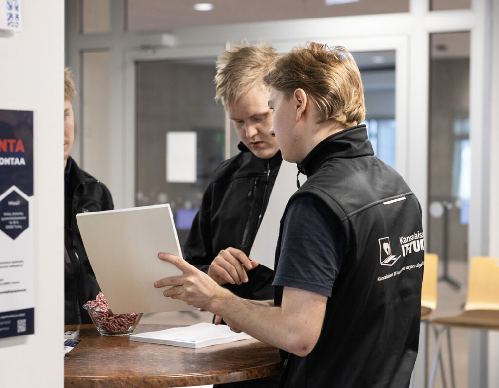 Kolme nuorta miesoletettua keskustelee jostakin.